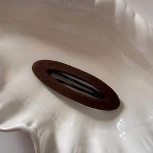 Gros plan d'une barrette en velours marron sur un plateau en céramique blanc