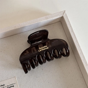 Detail view of dark brown translucent hair claw clip with golden Barrette La France text