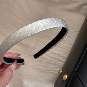 Detail of silver metallic textured headband with snake pattern and black lining