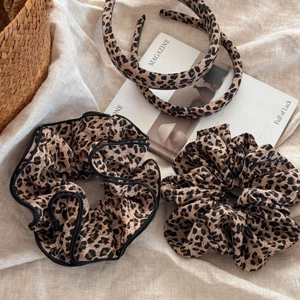 Leopard print hair scrunchies and headbands set with beige linen background decor