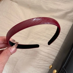 Detail of dark red faux leather headband with snakeskin texture and anti-slip lining
