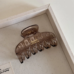 Detail view of amber translucent square hair claw clip with golden Barrette lettering