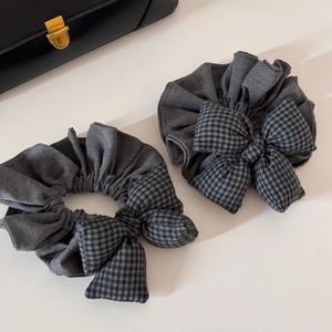 Détail de deux chouchous gris à carreaux avec nœud en tissu doux et élastique durable