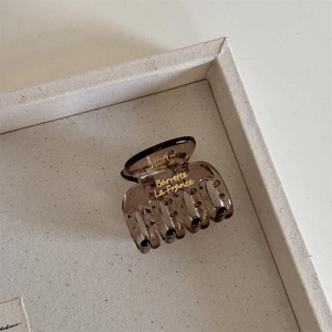 Macro shot of amber brown hair claw clip with golden Barrette La France text on white tray
