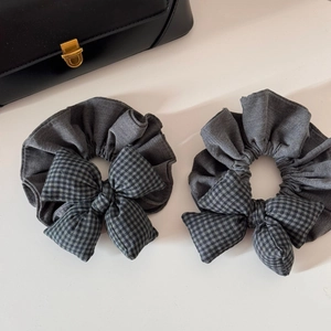 Lot de deux chouchous gris avec nœud à carreaux sur un fond épuré et sac en cuir chic