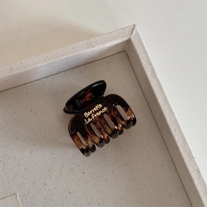 Detailed macro view of an amber tortoiseshell hair claw with golden Barrette La France text
