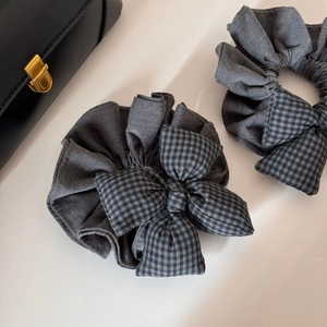 Détail de chouchous gris à carreaux avec nœud et texture tissée sur fond neutre