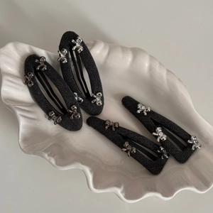 Close-up of grey fabric hair clips set with silver bows and rhinestones on shell tray