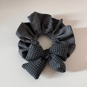 Détail du chouchou gris avec nœud à carreaux montrant la texture épaisse du coton
