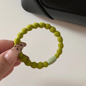 Primo piano di un elastico per capelli verde pastello con una perlina decorativa in plastica
