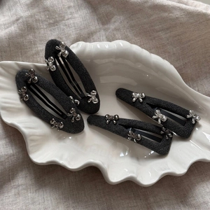 Close-up of grey herringbone fabric hair clips with silver bow and crystal accents