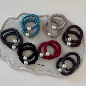 Close-up of pleated satin hair scrunchies in multiple colors with metallic charm detail