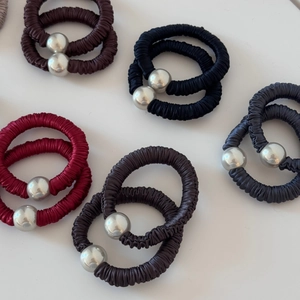 Close-up of pleated satin hair scrunchies with metallic beads in various dark tones