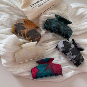 Assorted medium acetate claw clips in marble and tortoiseshell patterns on knit fabric