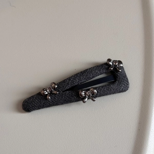 Detail of grey fabric BB hair clip with silver rhinestone metal bows and metal clasp