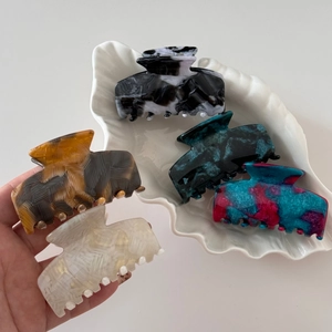 Detail of five medium tortoiseshell acetate hair claws on a decorative white shell tray