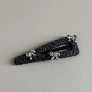 Detailed macro of gray fabric snap clip with three silver rhinestone bow accents
