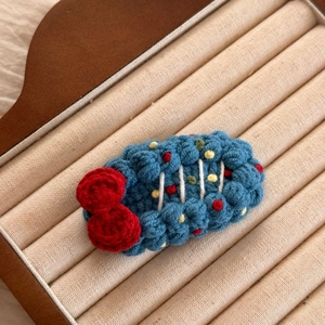 Détail d'une pince à cheveux en crochet faite main avec un nœud rouge et des pois colorés