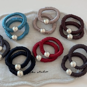 Flat lay of pleated satin hair scrunchies with metallic silver beads in various colors