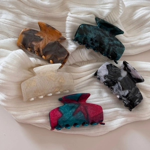 Set of 5 textured acetate hair claws in tortoise shell and marble patterns on white knit