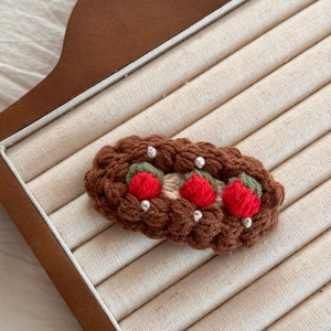 Gros plan détaillé d'une pince à cheveux crochetée à la main avec fraises et perles