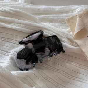Close-up of elegant black and white marble acetate hair claw clip on soft fabric