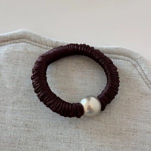 Detail of burgundy pleated silk hair scrunchie with a silver metallic bead accent
