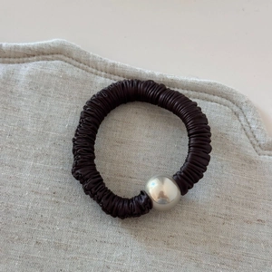 Detail of dark brown pleated satin hair scrunchie with a silver metal ball accent