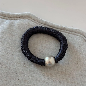 Detail view of black pleated satin hair tie with a polished silver metallic bead
