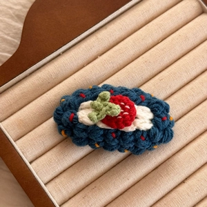Gros plan sur une barrette fraise crochetée main avec tissage alvéolé bleu foncé