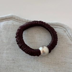 Detail of coffee pleated elastic hair tie with a shiny silver metallic pearl bead
