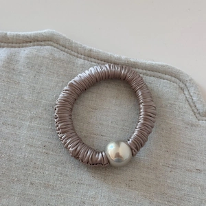 Detail of elegant champagne satin hair tie with pleated texture and silver metallic bead