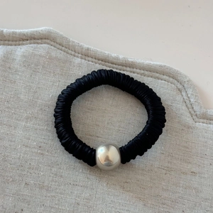 Detail of black pleated fabric hair scrunchie with a polished silver metallic bead accessory