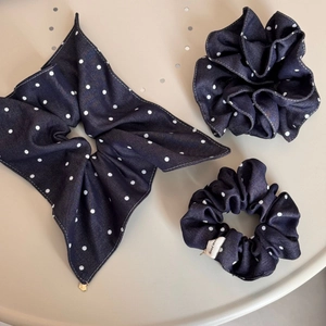 Close-up of three navy polka dot scrunchies set with a handmade label on a desk