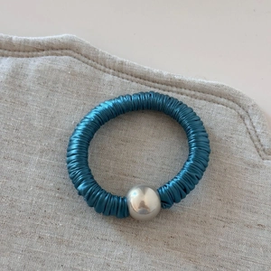 Detailed view of dark blue silk texture hair tie with a silver mirror finish bead accent
