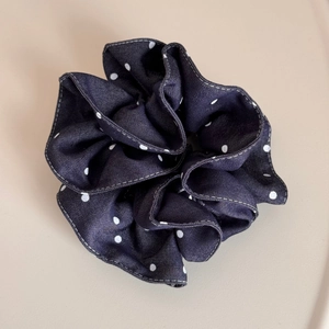 Detailed texture of navy blue polka dot denim scrunchie with white contrast stitching