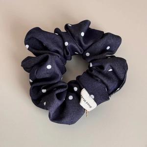Detail of navy blue polka dot scrunchie with handmade label and gold bead charm