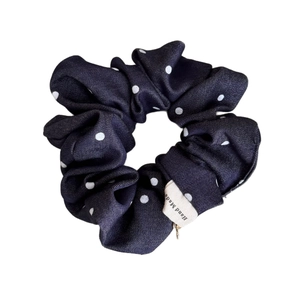 Navy blue denim fabric scrunchie with white polka dots and a handmade fabric label