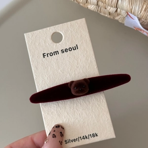 Detalle de una pinza para el pelo roja con un lindo oso de peluche marrón en tarjeta