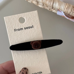 Detalle de una cabeza de oso flocada marrón en una pinza de pelo de terciopelo negro