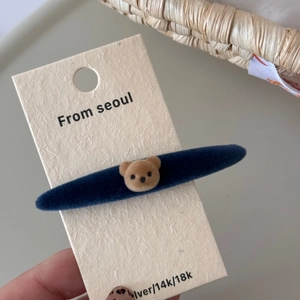 Detalle de una pinza para el pelo con osito aterciopelado en una etiqueta beige