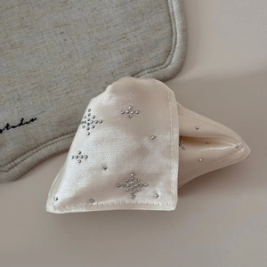 Close-up of cream satin hair claw clip with star-shaped rhinestones and fine texture