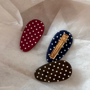 Close-up of three oval polka dot hair clips in burgundy, navy blue, and coffee resin