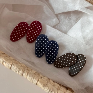 Set of six oval polka dot hair clips in red, blue, and brown on white decorative paper