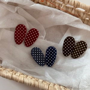 Close-up of retro oval polka dot hair clips in red, blue, and brown in a woven basket