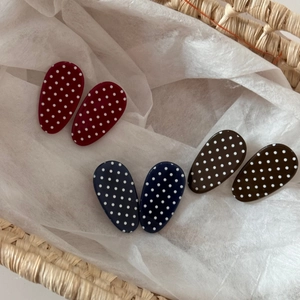 Close-up of retro oval polka dot hair clips in red, blue, and brown resin set