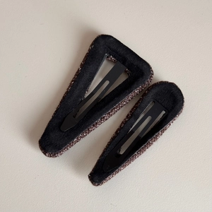 Detailed macro view of tweed wrapped triangular hair clips with soft velvet inner lining