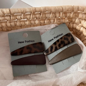 Chic leopard print and solid leather BB hair clips set on woven texture background
