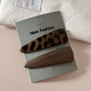 Close-up of leopard print fabric and brown leather triangle hair clips on display card