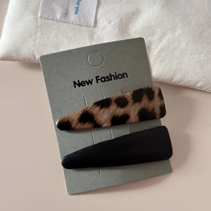 Detail shot of leopard print and black leather snap hair clips on a display card